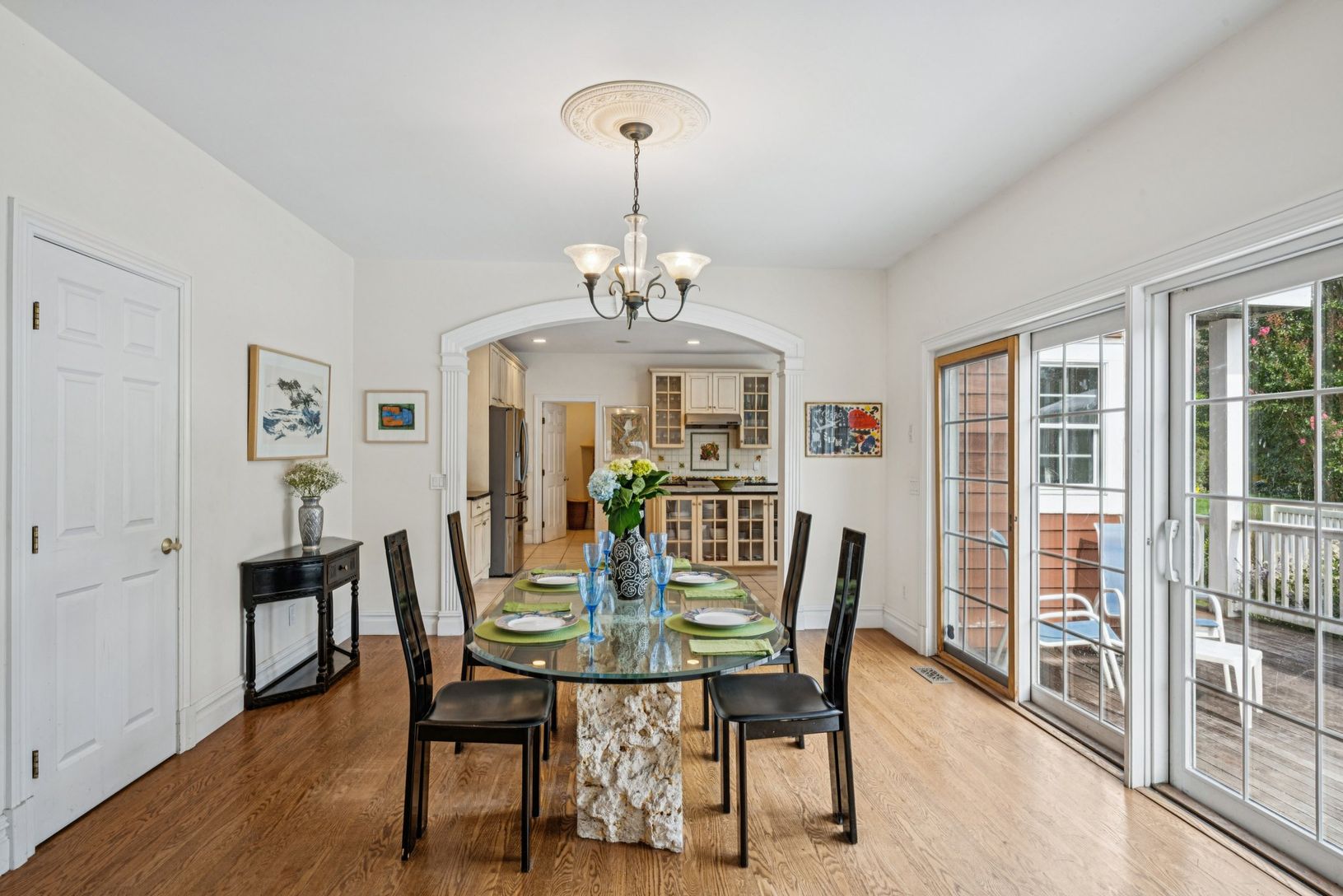 Sophisticated dining area adorned with arched walkways, wood-finished floors, and a chandelier.