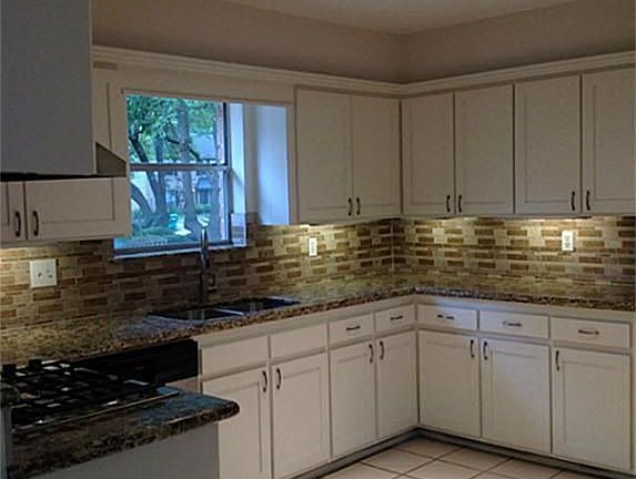 New Granite and wonderful backsplash show off this open and bright kitchen with new lighting, under-