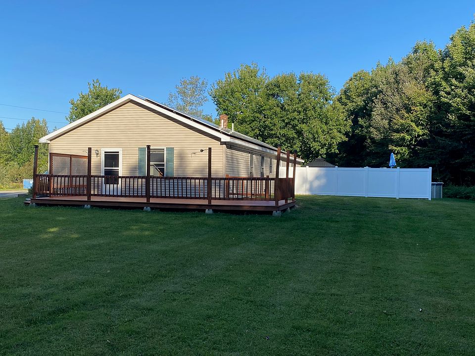Side view and backyard with privacy fence, Large lawn area surrounded by trees.
