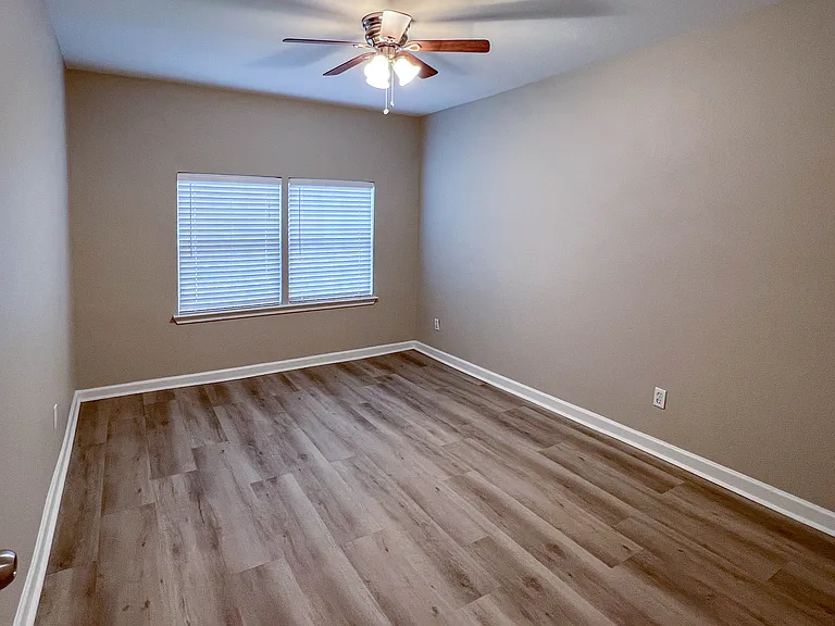 Third bedroom with wood-look flooring, ceiling fan, and plenty of natural light.