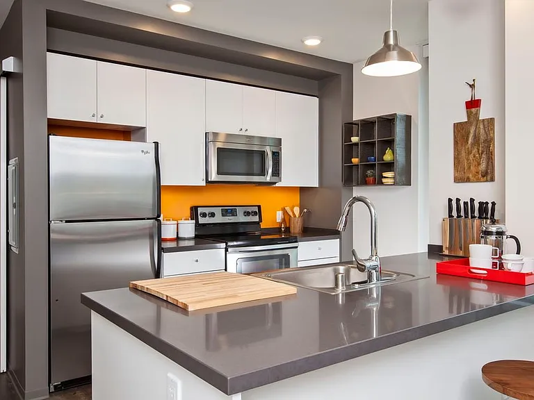 Kitchen with white cabinetry, chrome countertop and stainless steel appliances