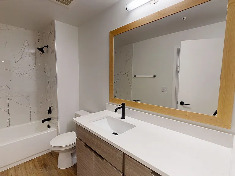 Apartment bathroom with wood-style flooring.
