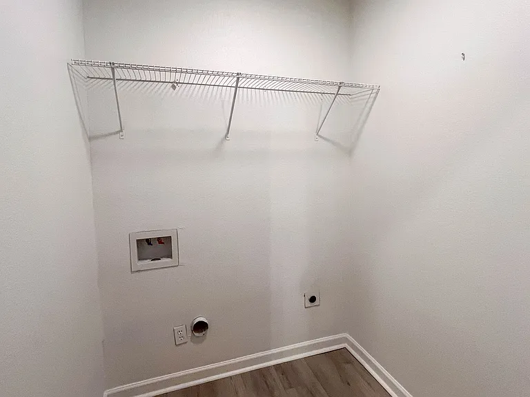 Laundry space with washer and dryer connections plus built-in shelving for added storage.