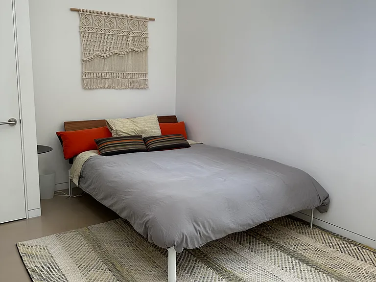 This guest bedroom has a high ceiling, clearstory windows bathing the room with natural light, queen size bed, & a sitting area. It has its own guest bathroom directly across the hall.