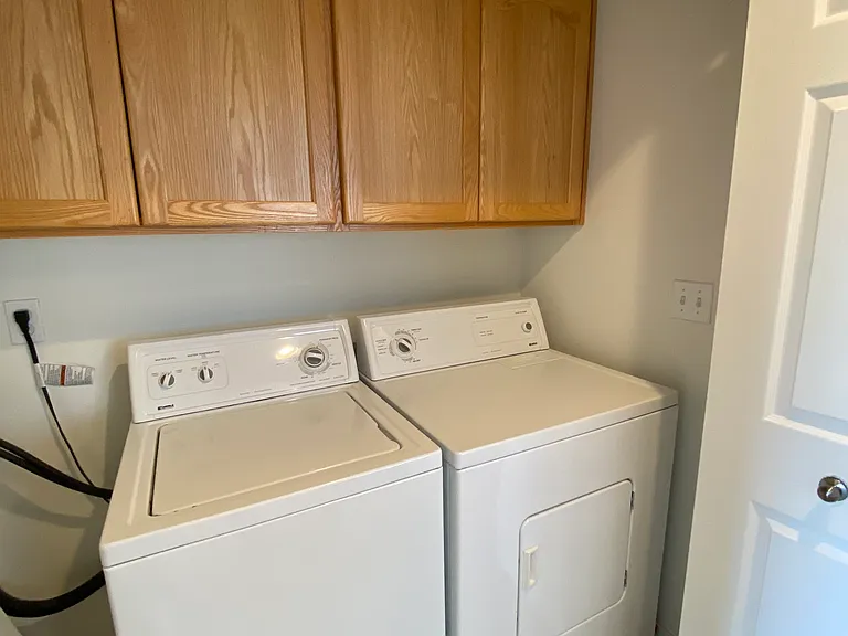 Laundry closet with cabinets and full size appliances.