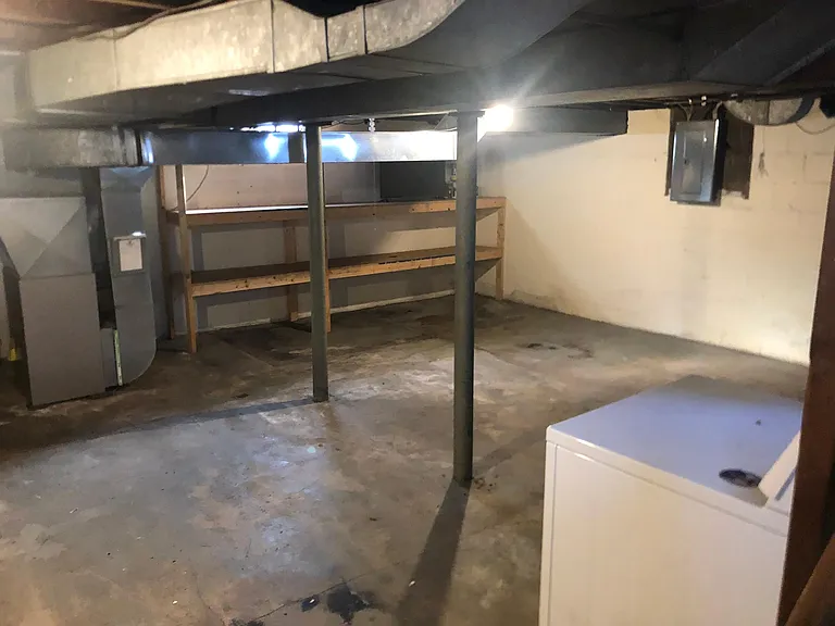 View of storage area in the utility basement with cement floors.