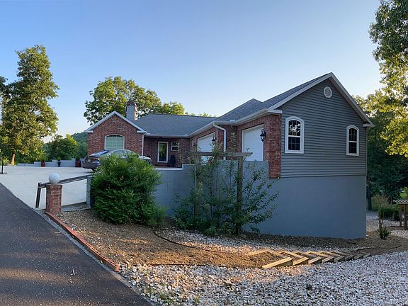 Driveway in front of house with steps leading to backyard fire pit