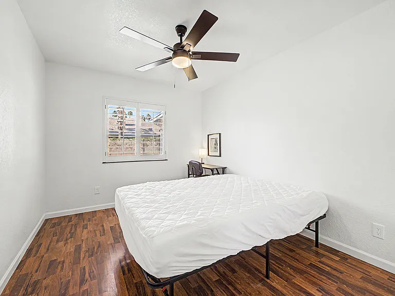 Wood flooring, Queen Bed, desk, chair, lamp, fan, mirrored closet.