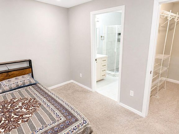 Bedroom with carpet flooring, neutral walls, and direct access to a private bath plus an open closet for easy storage.