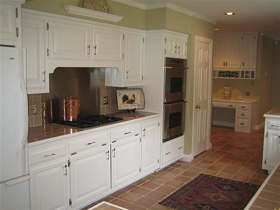 The kitchen features terra cotta tile, stainless steel backsplash and applian