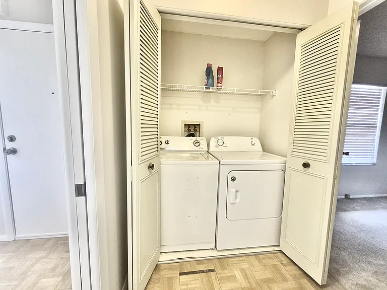 Washer, dryer laundry space enclosed in passage. Privacy sliding door on the left.