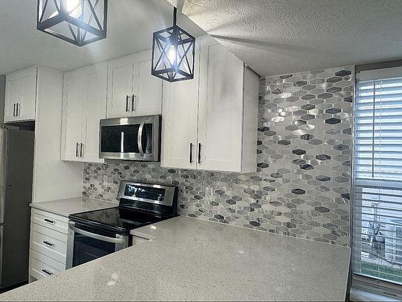 New backsplash, new quartz countertops with an overhang for seating, new soft-close cabinets & drawers, new lighting