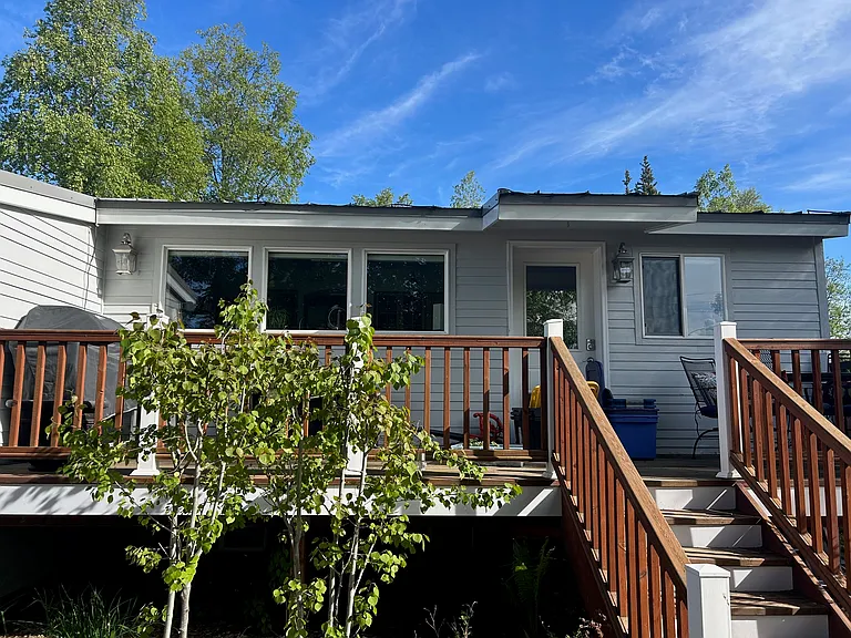 Back deck with table, chairs, and grill. Steps lead to garden with herbs and veggies.