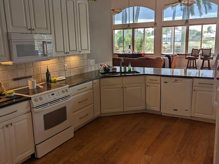 Kitchen, view from garage entrance. Kitchen has 22-foot ceilings, abundant storage, granite countertops and a large walk-in pantry.