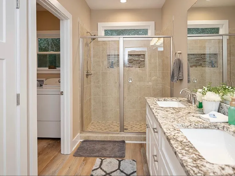 master bathroom with walk in shower and double sinks and a closet
