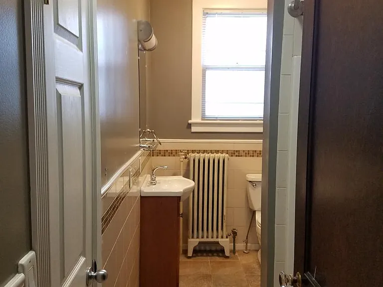 Bathroom from hallway very bright cheerful with ceiling fan and high ceilings