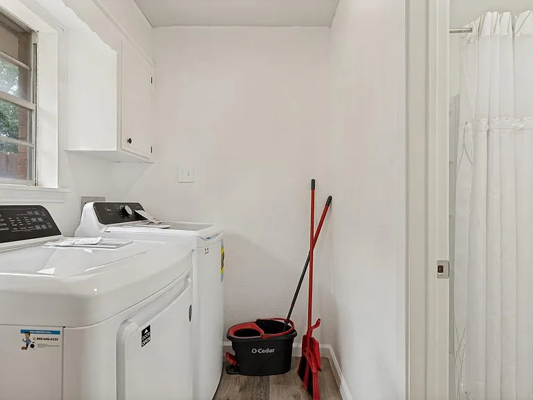 Convenient in-home laundry area with side-by-side washer and dryer, plus nearby storage and easy access to the bath.