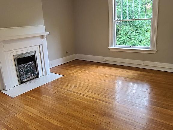 Large living room with hardwood floors, large windows overlooking the treed median on Hampton Court. Fireplace is a focal point, not for burning logs. Overhead remote controlled fan with light.