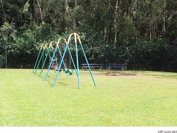 Playground and benches to sit on in front of forested background.
