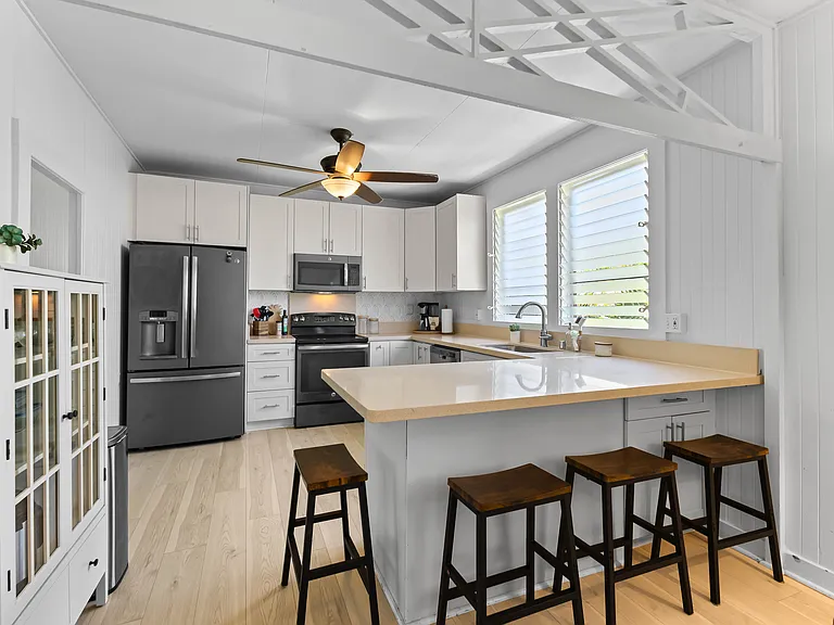 The kitchen is open to the living room and features plenty of storage and counter space, a ceiling fan, full size refrigerator with water station, oven, microwave and dishwasher. The kitchen is fully equipped.