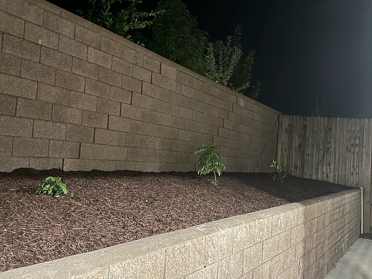 Backyard with retaining wall and plants and weed protection with fabric and bark (mulch)
