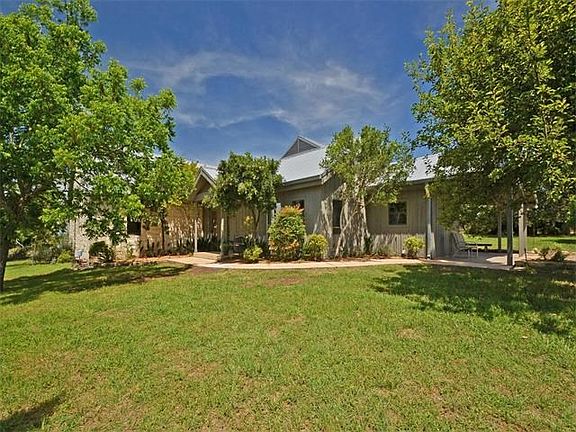 The rustic charm of this exterior stone home blends effortlessly with the Hill Country background.