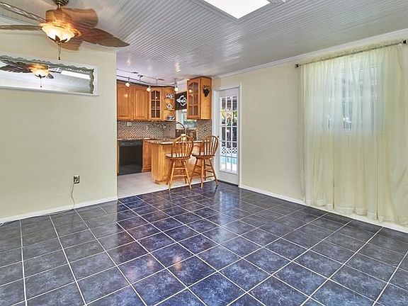 Living room with skylight is very light and bright. Freshly painted, with ceiling fan and ceramic tile flooring.