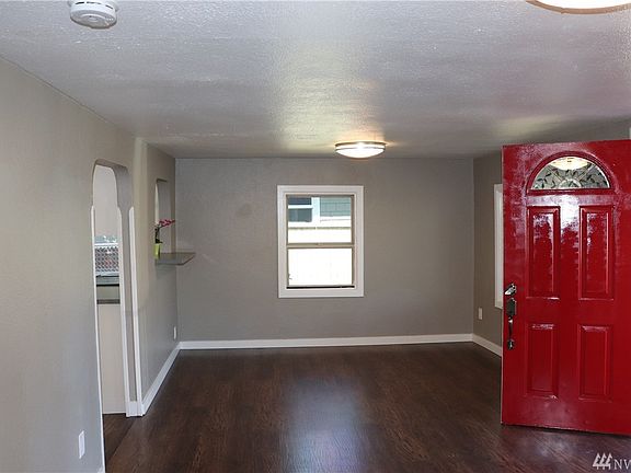 Bright Red Door Welcomes You and Invites You in to this Good Sized Living Room and Kitchen in the Distance.