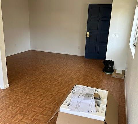 View from spacious dining area toward living room and front door. 
 Large window on right wall. The microwave is sitting in dining area in box, awaiting installation.
