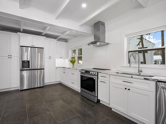 Sleek white cabinetry meets high-end stainless appliances and beautiful architectural ceiling details.