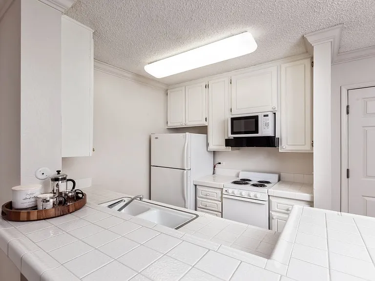 Classic Package I kitchen with white appliances, white cabinetry, and white tile countertop, and vinyl flooring (select homes)