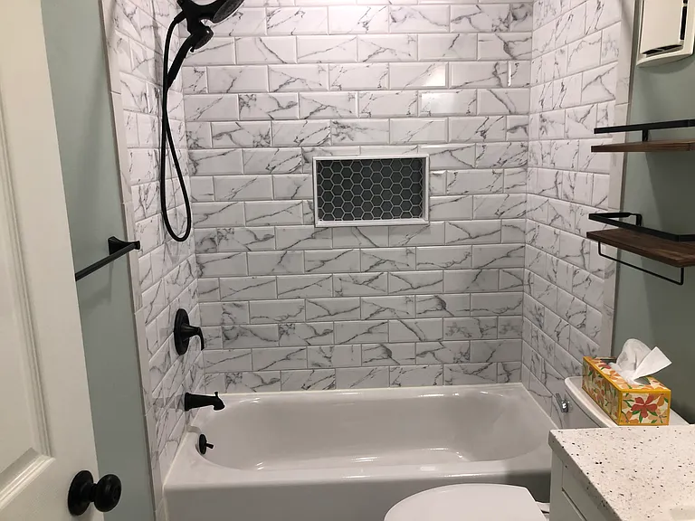 new tub, tile, and toilet in hallway bathroom