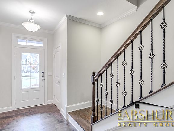 Front entry foyer featuring engineered hardwood flooring, oak tread staircase and wrought iron