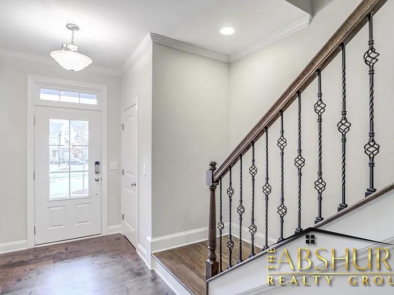 Front entry foyer featuring engineered hardwood flooring, oak tread staircase and wrought iron