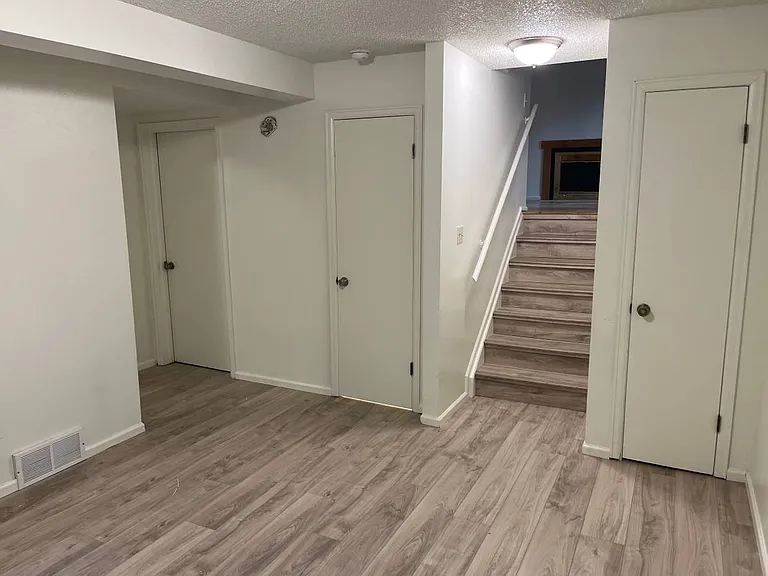 lower living room showing stairs up, utility, bathroom and storage entrances