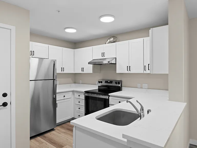 Bright modern apartment kitchen with white cabinets, stainless steel appliances, quartz countertops, and an open layout. Bright modern apartment kitchen with white cabinets, stainless steel appliances, quartz countertops, and an open layout.