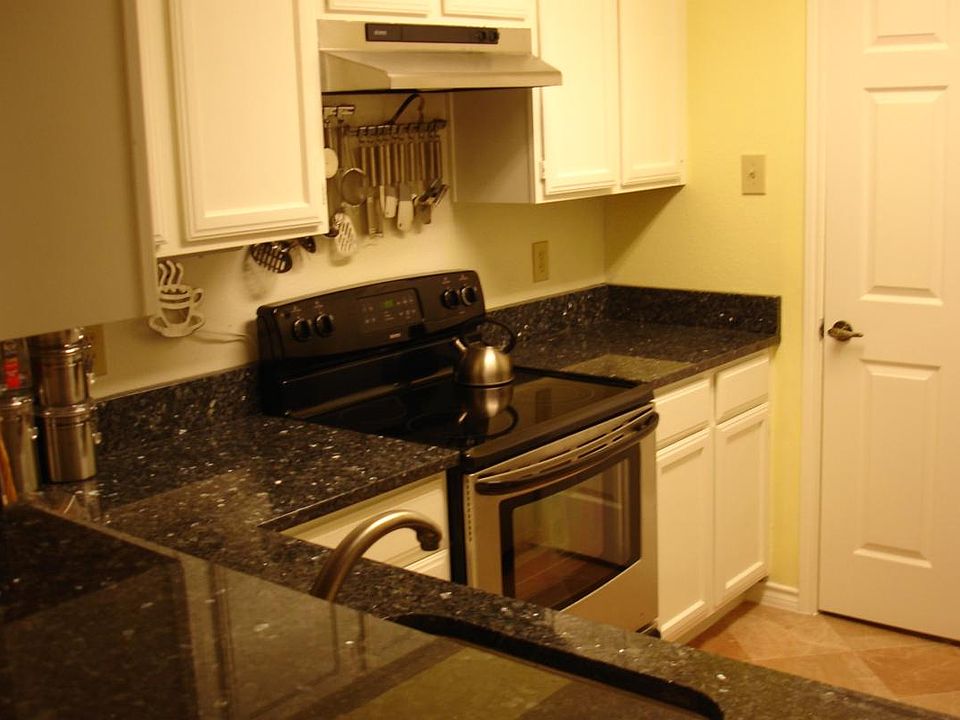 Kitchen with Granite Countertops, Stainless Steel Appliances, and Marble Tiles