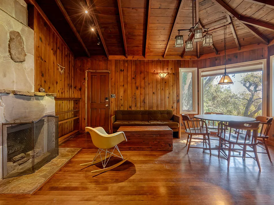 Living room with working gas fireplace and bay window with ocean and tree views. Room has its own mini split for cooling and heating. Top down bottom up blind on bay window. Furniture not included in rental.