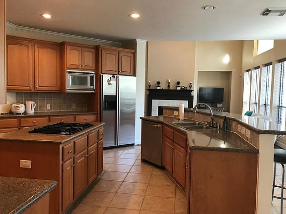 Kitchen with island, SS appliances, tile floors.