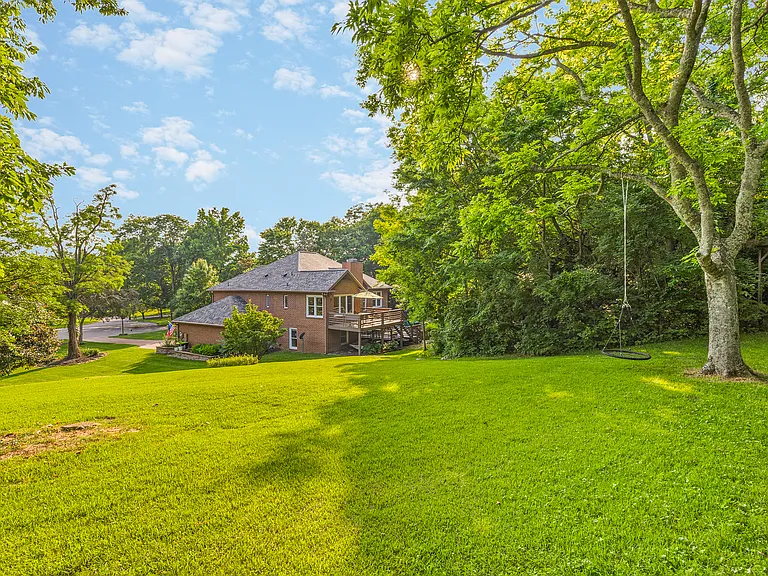 Huge backyard with a swing on an oak tree.