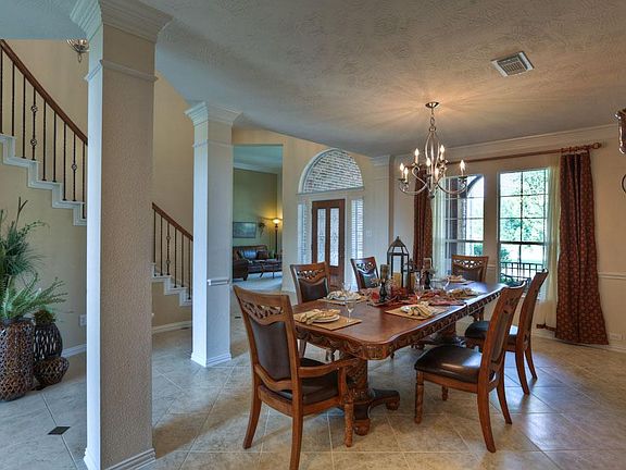 View of the stunning entry foyer with curved staircase from the formal dining, flanked by columns, allows you to see the formal living room as well.