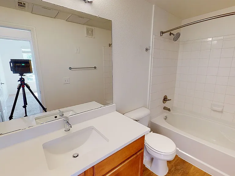 Apartment bathroom with wood-style flooring. Quartz-style countertops (shown here) are available in select homes.