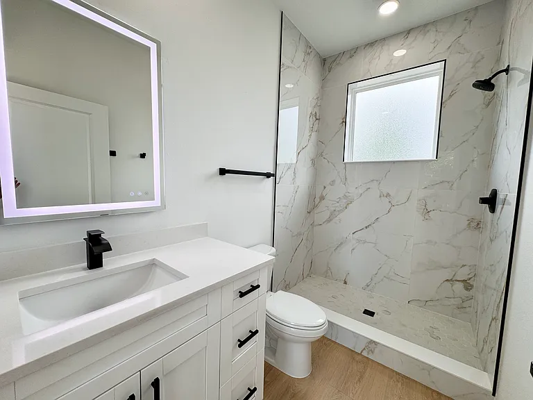 Sleek bathroom with walk-in shower and LED vanity mirror.