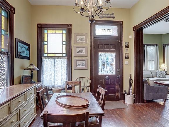 Front foyer with the front door with its door chime under the glass panel and large transom above. Stained glass windows. Large doorway going into the living room to the right.