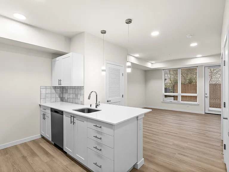 Bright open-concept layout featuring a modern kitchen, pendant lighting, and spacious living area with patio access. Bright open-concept layout featuring a modern kitchen, pendant lighting, and spacious living area with patio access.