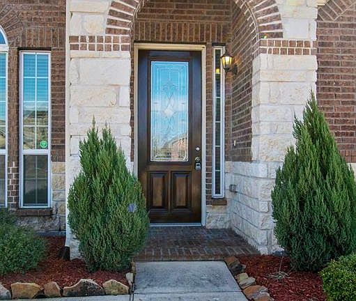 A path leads you through to a decorated glass front door. This welcoming front porch greets your guests.