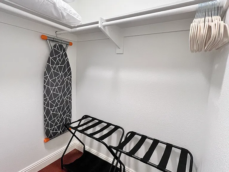 Spacious Walk-in Closet with iron, ironing board, luggage racks, velvet hangers, extra pillows, and a rolling laundry basket everything you need to stay organized and comfortable.