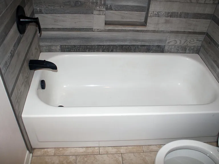 Fully remodeled second bathroom tub and shower with wall-to-wall imported tile and bronze fixtures.