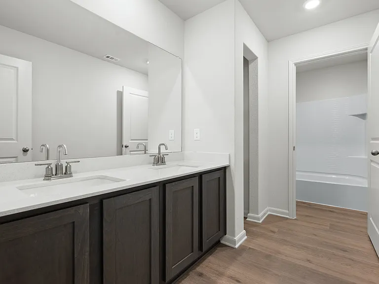 The secondary bathroom has a sprawling, dual-sink vanity and shower tub combo.