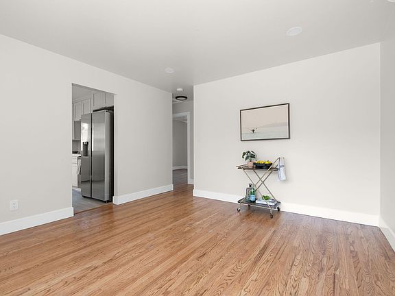 View from living room into kitchen on the left and view of hallway to 2 bedrooms and hall bath